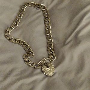 A silver chain link necklace with a heart